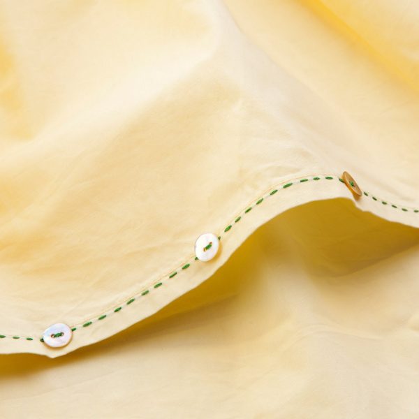 Close-up of the hi lo hem of yellow applique cotton dress with a hand embroidered kantha edging