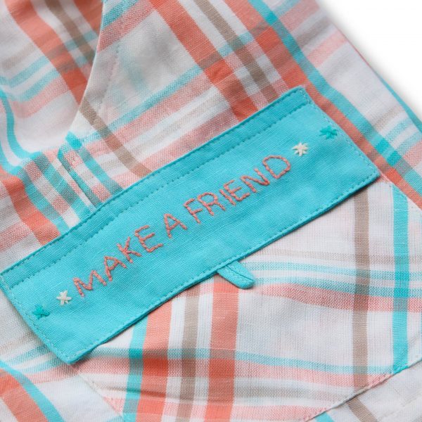 Close-up of melon sorbet plaid shorts with hand embroidered message on pocket flap