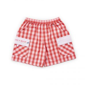 Flatlay of checked shorts with hand embroidered message on pocket flap and elastic waist