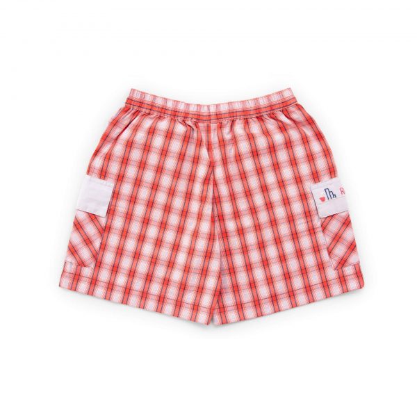 Flatlay of red and grey plaid cotton shorts with hand embroidered message on pocket flap and elastic waist
