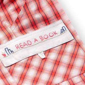 Close-up of the hand embroidered message "Read A Book" on the pocket of red plaid shorts