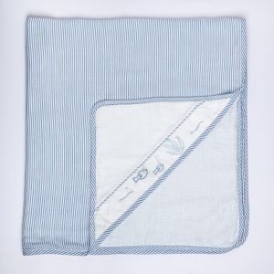 Flatlay of baby blue infant head wrap with hand embroidered motif in corner flap and contrast piping along edges