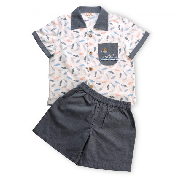 Flatlay of fish print shirt with hand embroidered design on pocket and wood buttons paired with grey shorts