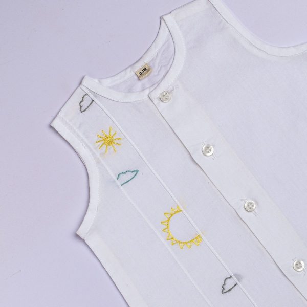 Close-up of hand embroidered sun and clouds in white infant cotton jabla