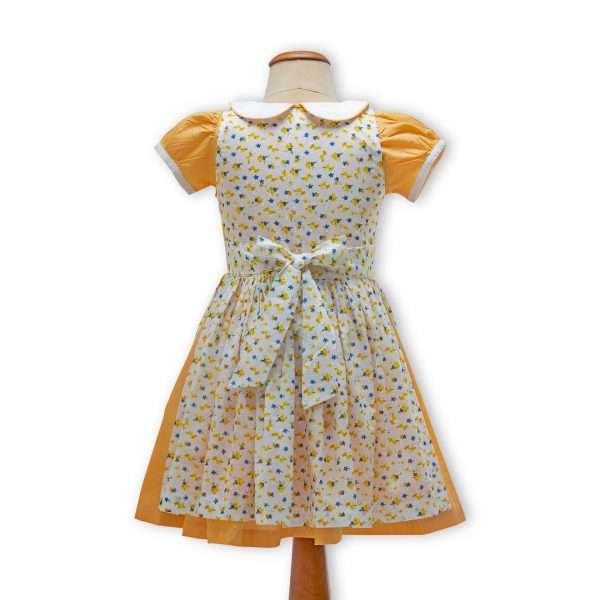 girls dress in orange gingham on a mannequin with a floral apron overlay
