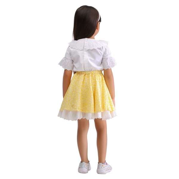 Back view of a girl dressed in a lace edged yellow printed umbrella skirt with a white clouse with gathered lace edged sleeve and a lace neck rufle