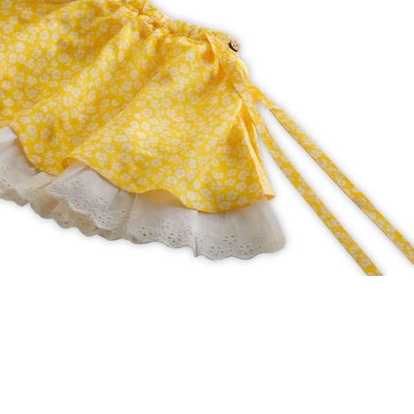 Close up image of yellow floral flared skirt with eyelet lace trims at hems and tie-up sash
