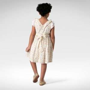 Rear image of a girl in swiss-dot floral dress with hand-smocked waistline and eyelet lace trims