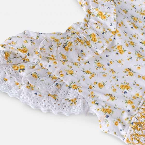 Close-up of swiss-dot floral dress with hand-smocked waistline and eyelet lace trims in flutter sleeves