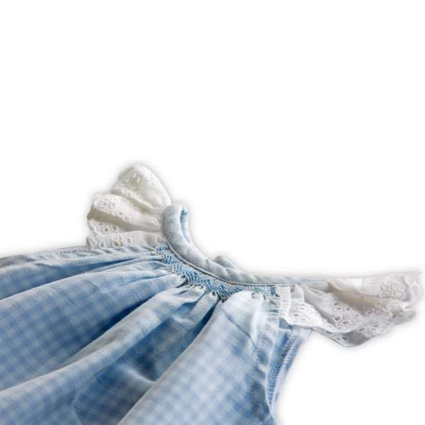 flatlay of an infant bishop in blue gingham with a smocked neckline, angel sleeves in vintage eyelet lace