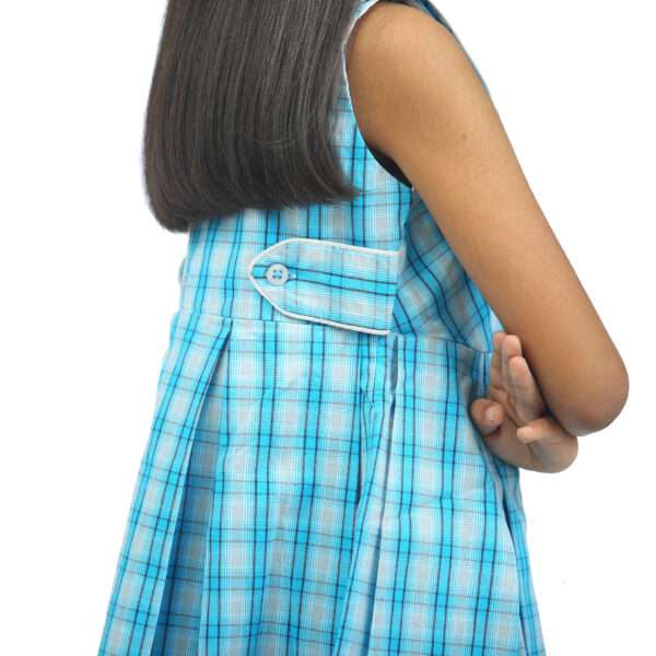 Side view of a girl wearing a blue plaid dress with side tabs at waist