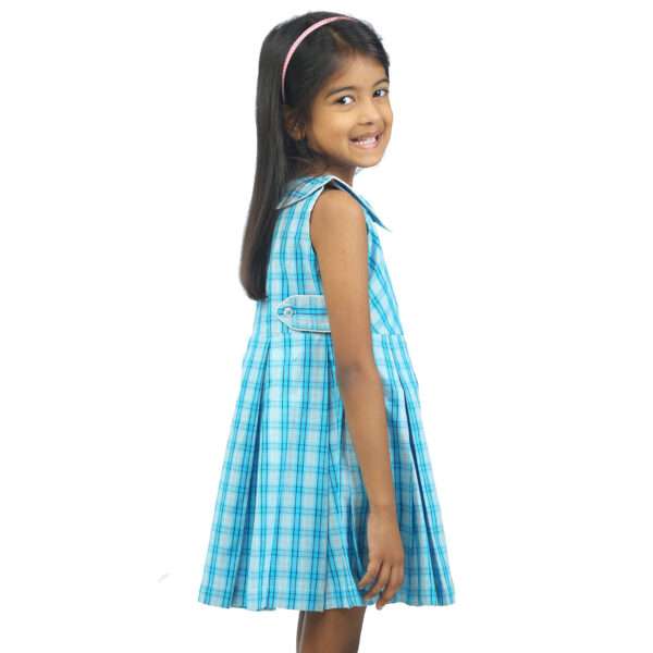 Side view of a little girl in light blue plaid dress with two tone hand embroidered collar and back tabs