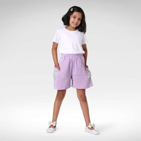 Girl poses with hands in the pockets of lavender check shorts
