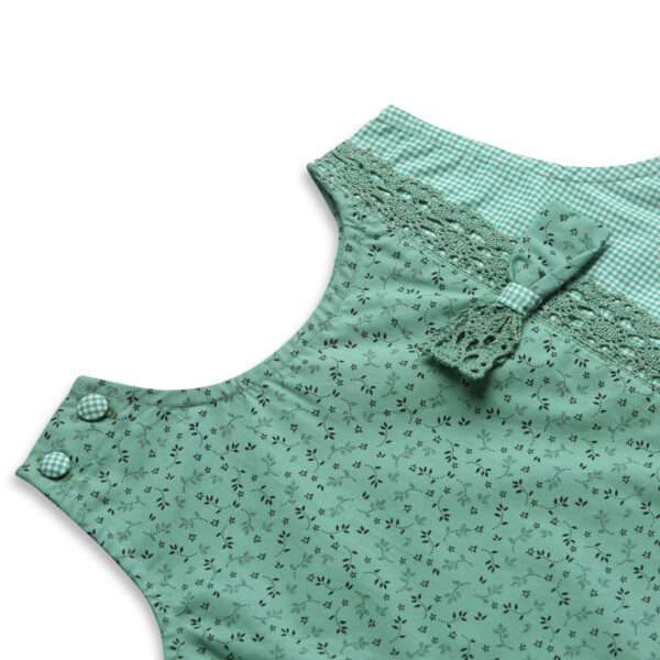 Close up of jade green tunic with shoulder button fastening, faux-crochet trim with a matching bow and matching shorts