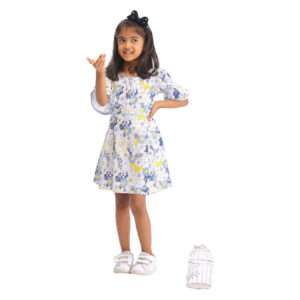A young girl wearing swiss dot blue floral printed cotton dress with boat neck and elasticated shirring on bell sleeves