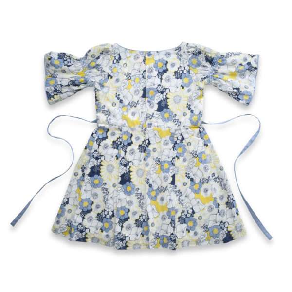 Rear side flatlay of swiss dot blue floral printed cotton dress with elasticated shirring on bell sleeves