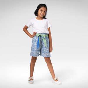 A little girl wearing blue floral paperbag shorts with reversible cloth belt