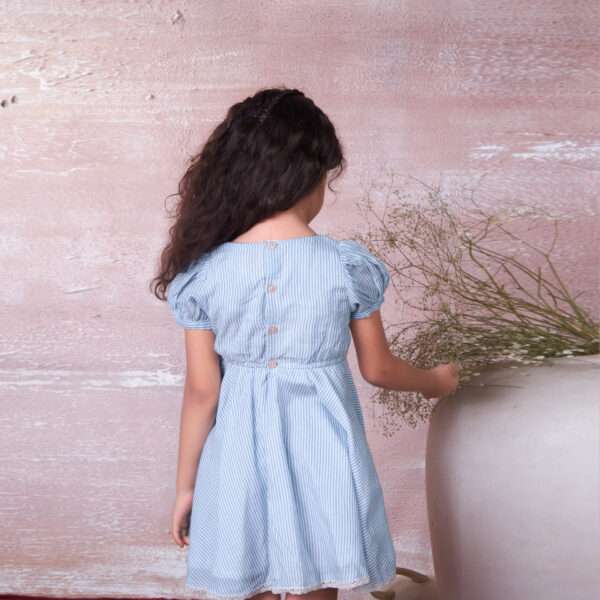 Rear image of a girl in striped blue muslin dress with waist elastication and puff sleeves