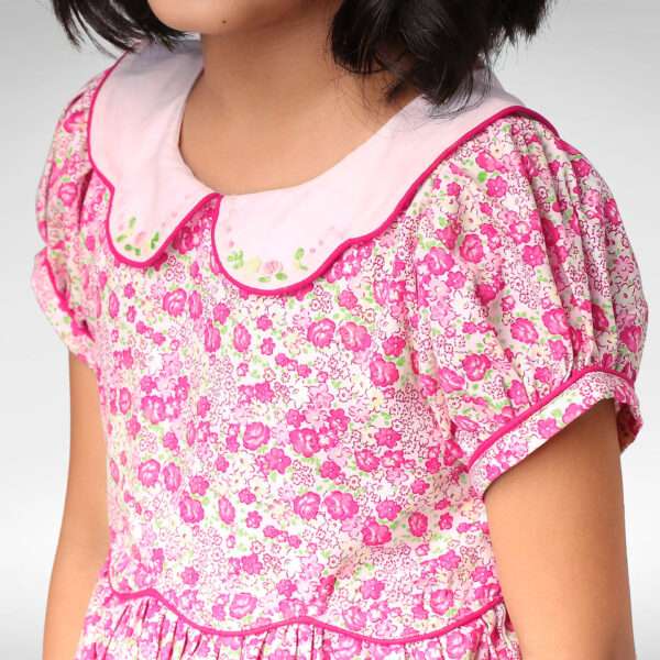 Close up of a scallop collar on a girls dress with small pink bullion rose embroidery