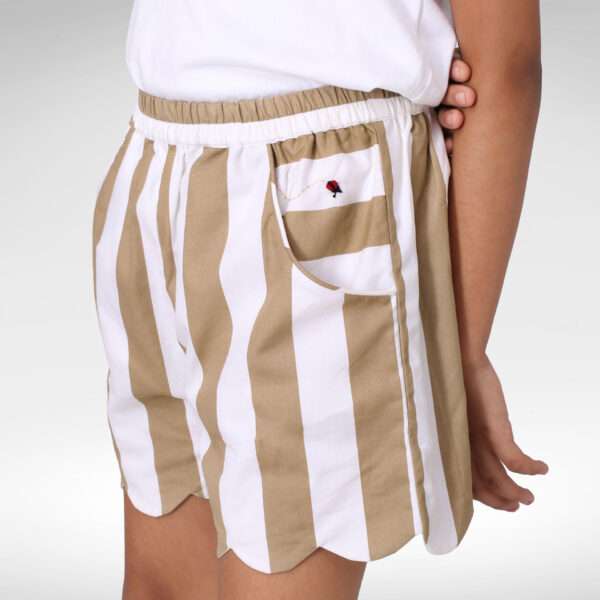Close-up of a child in tan striped cotton shorts with hand embroidery and scalloped hem