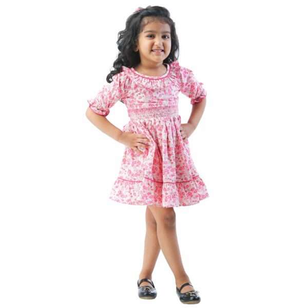 A little girl in floral printed cotton dress with a hand-smocked waistline, puff sleeves, ruffled collar as well as hem