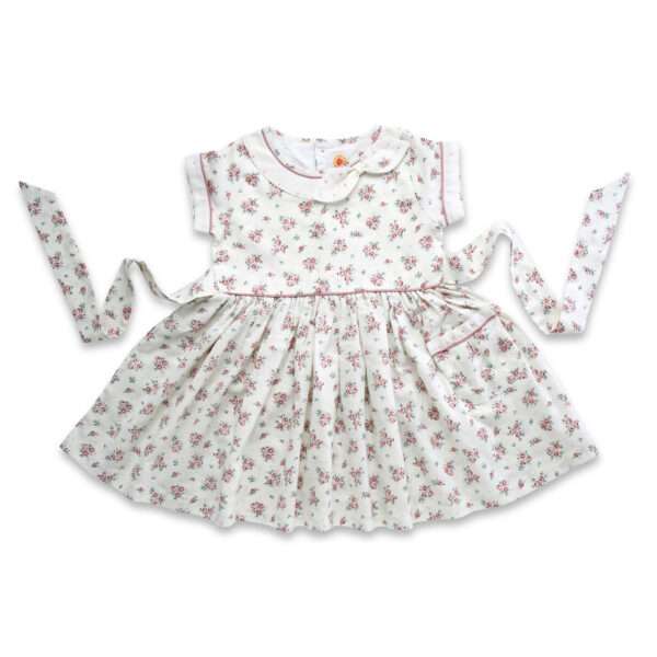 Flatlay of ivory floral dress with faux collar and bow with hand embroidered dots