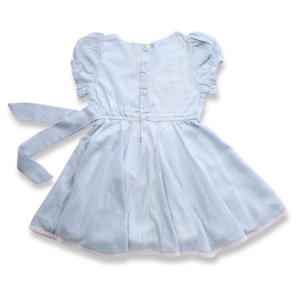 Flatlay of rear side of blue striped cotton crossover dress with crochet-style lace trim, floral hand-embroidery