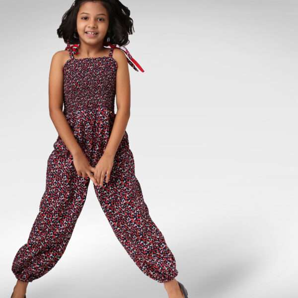 A jolly girl in floral printed jumpsuit with a shirred elasticated yoke, shoulder-ties, and cinched cuffs at the ankle