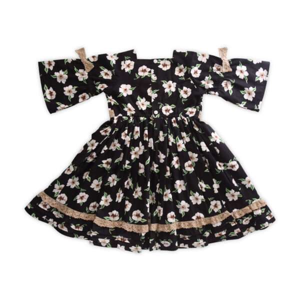 Rear flatlay of black floral dress with bell sleeve, tan lace bows and lace trim on the hem
