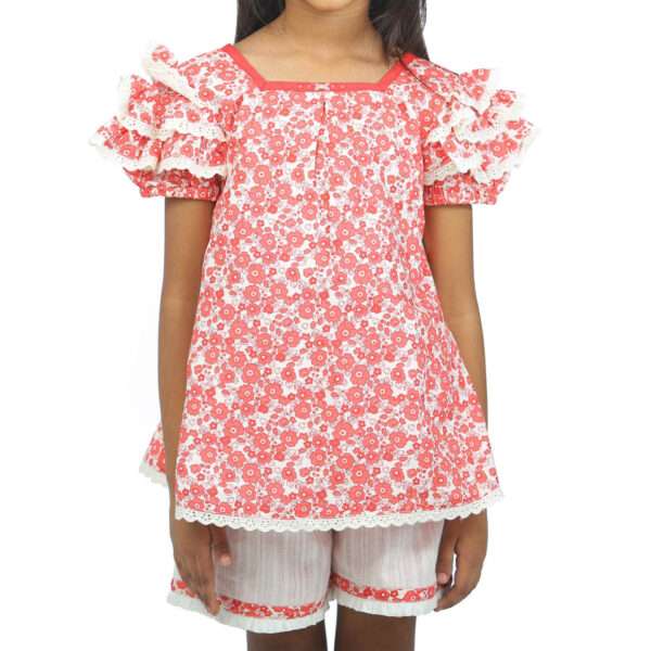 A little girl in red floral viscose tunic with hand embroidered neckline paired with ivory cotton shorts