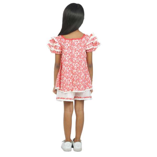 Back view of girl wearing a coral tunic and ivory shorts set with ruffles and lace trims