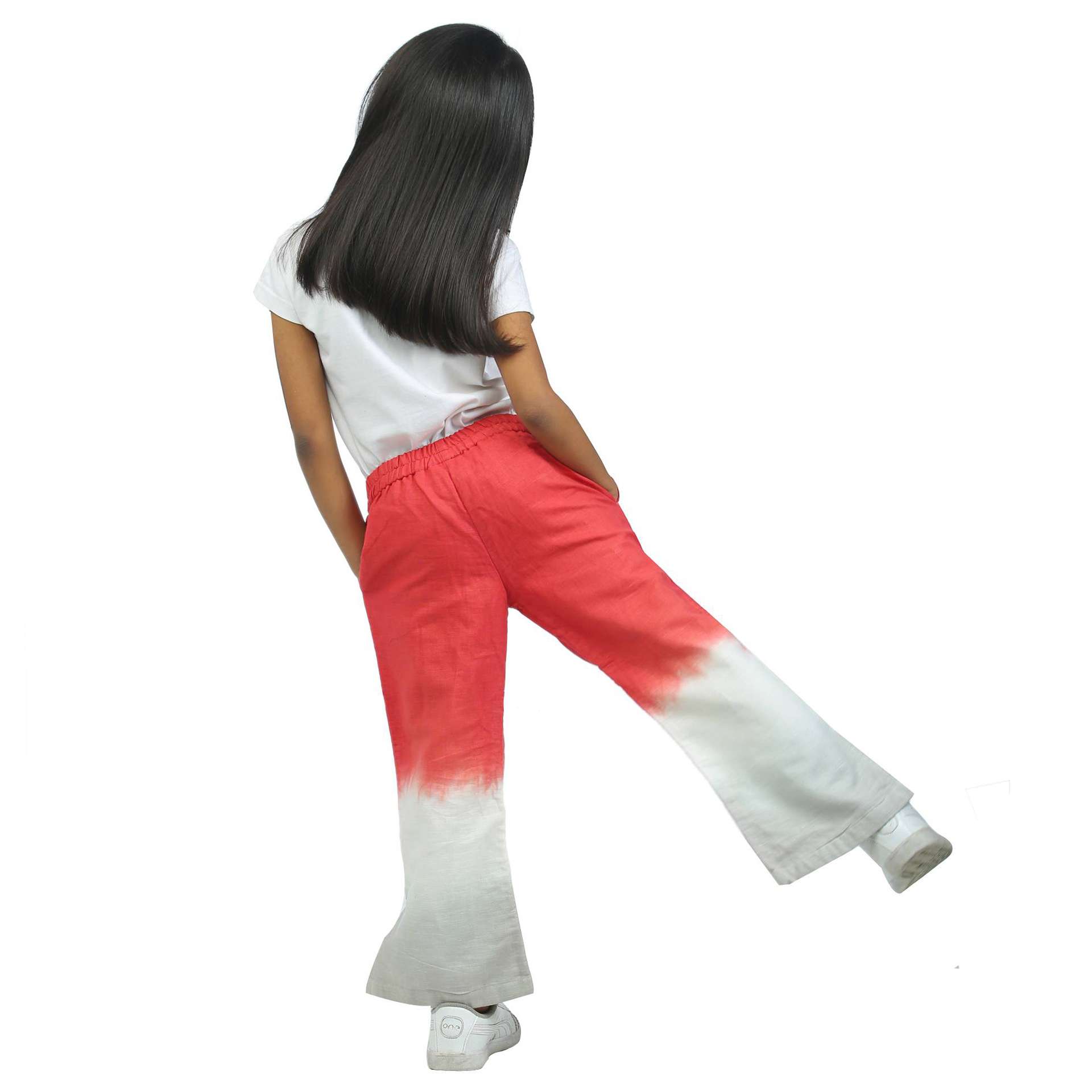 Rear image of a girl in tie dye linen bootleg pants in coral and grey, with soft elasticated waistband and side pockets