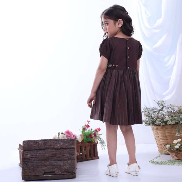 Rear image of a girl wearing brown twill dress featuring a broad floral neckline embroidery