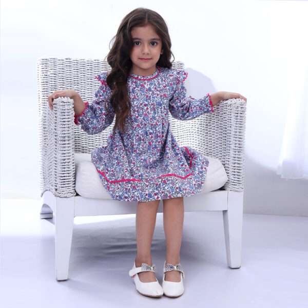 Girl seated on a chair wearing a blue floral print long sleeve dress
