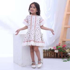 A little girl in drop waist cotton floral dress with hand embroidered details and lace