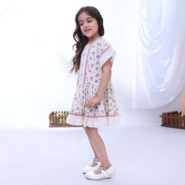A girl in ivory cotton poplin dress printed with a floral spray, with hand-embroidered flower details