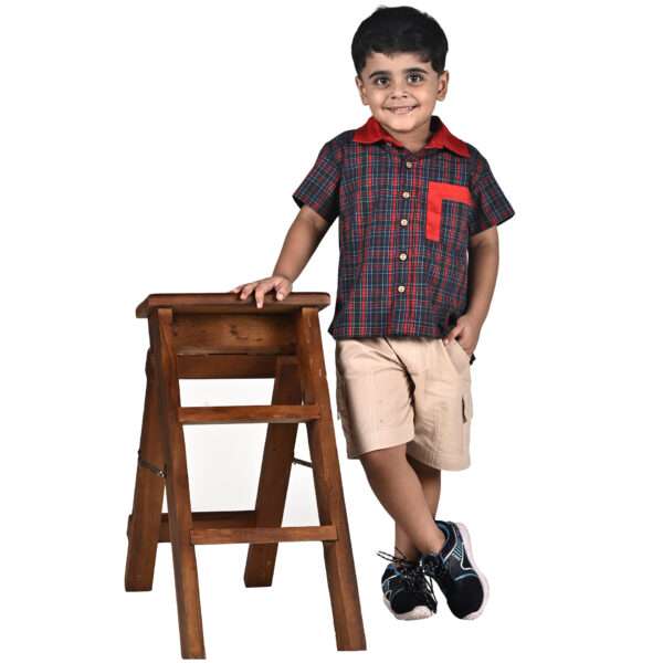 Small boy stands by a step ladder wearing a tartan shirt and khaki casual cargo pocket shorts