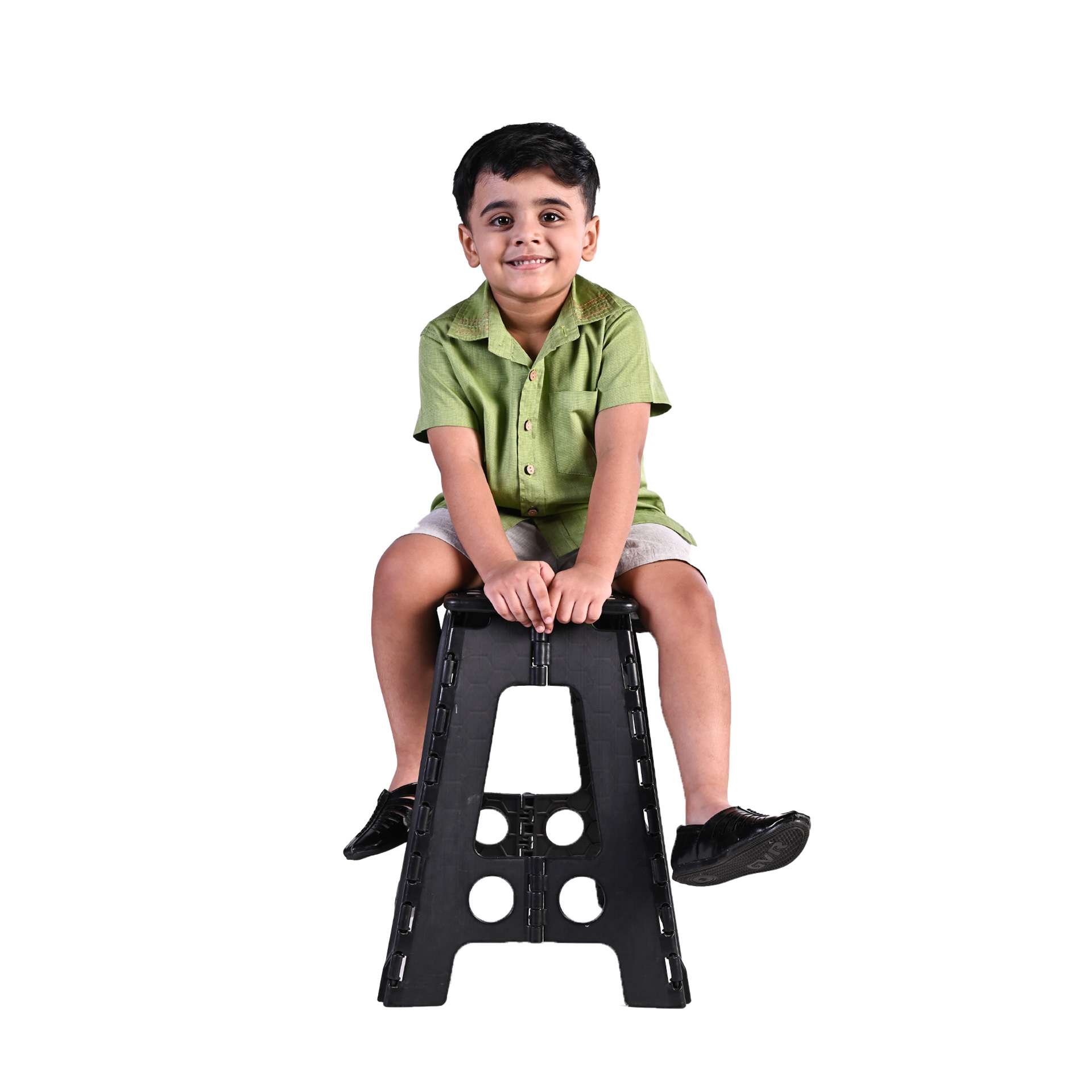 Boy sits atop a stool wearing a leaf green half sleeve shirt and khaki shorts