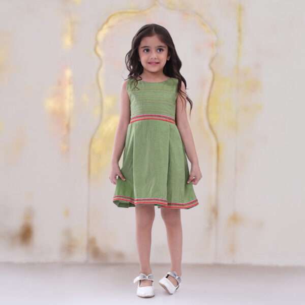 A little girl in green sleeveless dress with hand embroidered kantha work on bodice