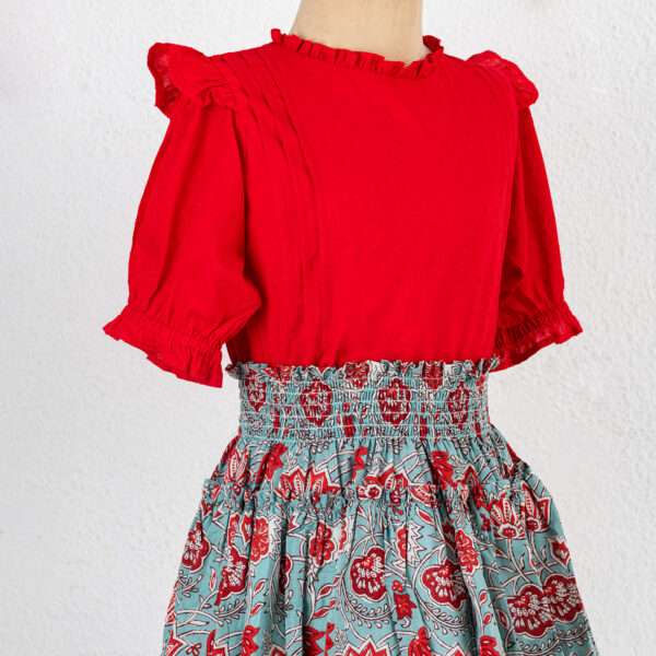 Mannequin image of teal and coral chinoiserie print skirt with blouse in red swissdot with ruffled collar