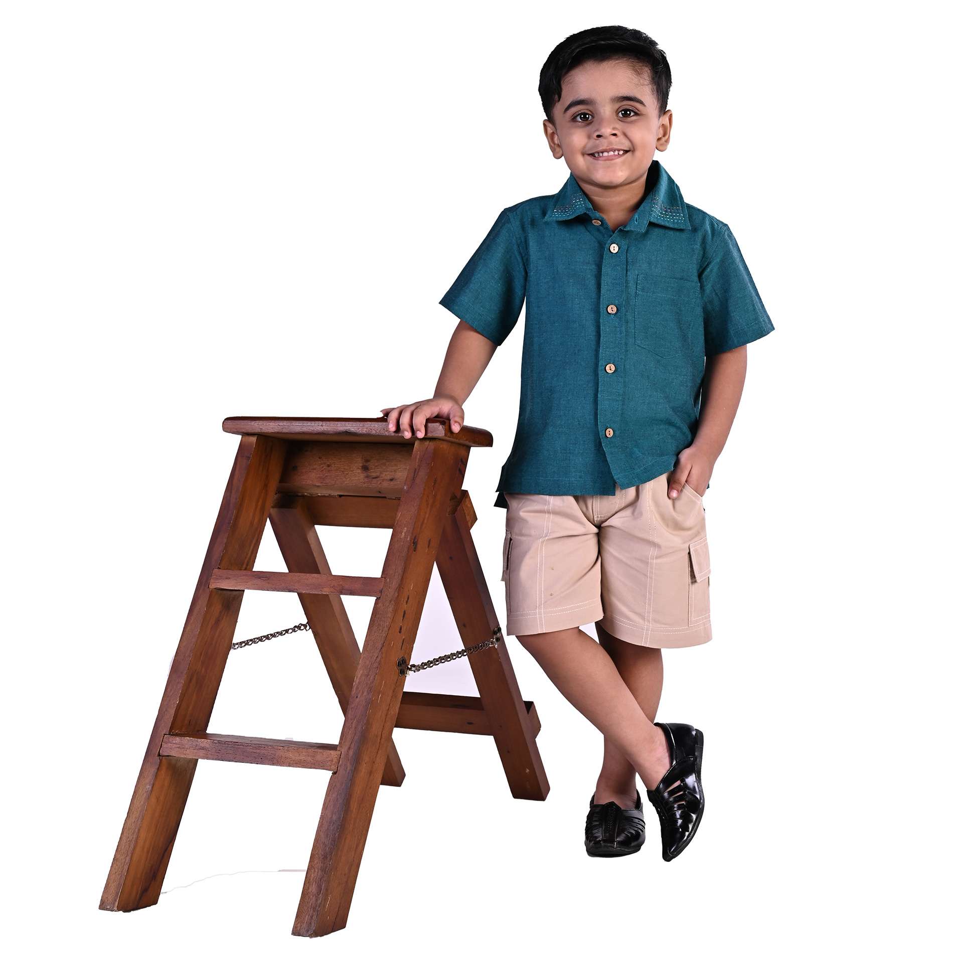 Boy poses by a step ladder wearing a dark teal shirt and khaki casual cargo shorts