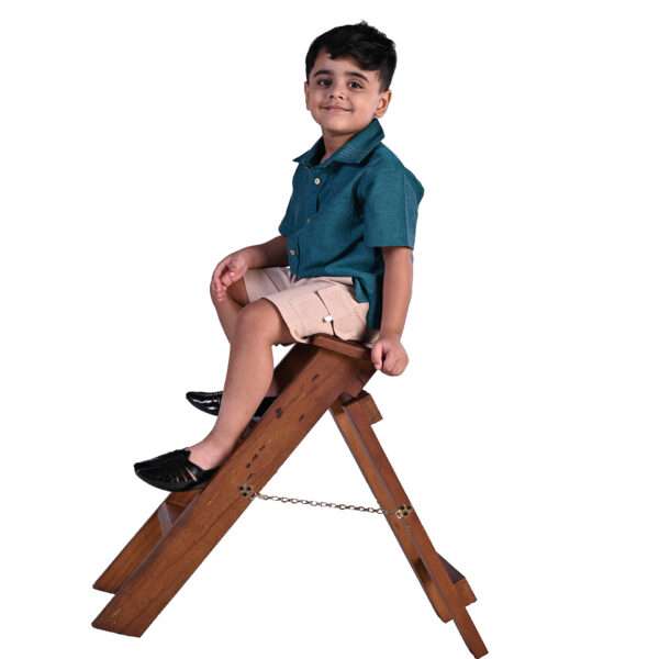 Boy sits on a ladder wearing a half sleev shirt and shorts