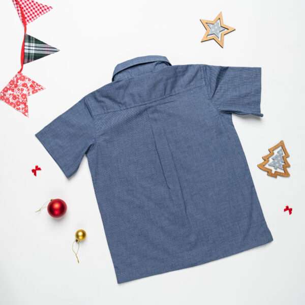 Back view of a navy boys shirt with a central pleat and Christmas decorations strewn around