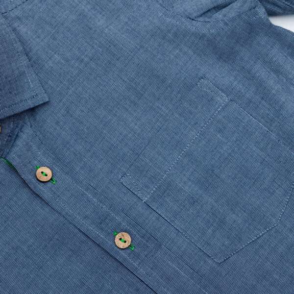 Close up of blue button down shirt with front pocket and wood buttons down the front