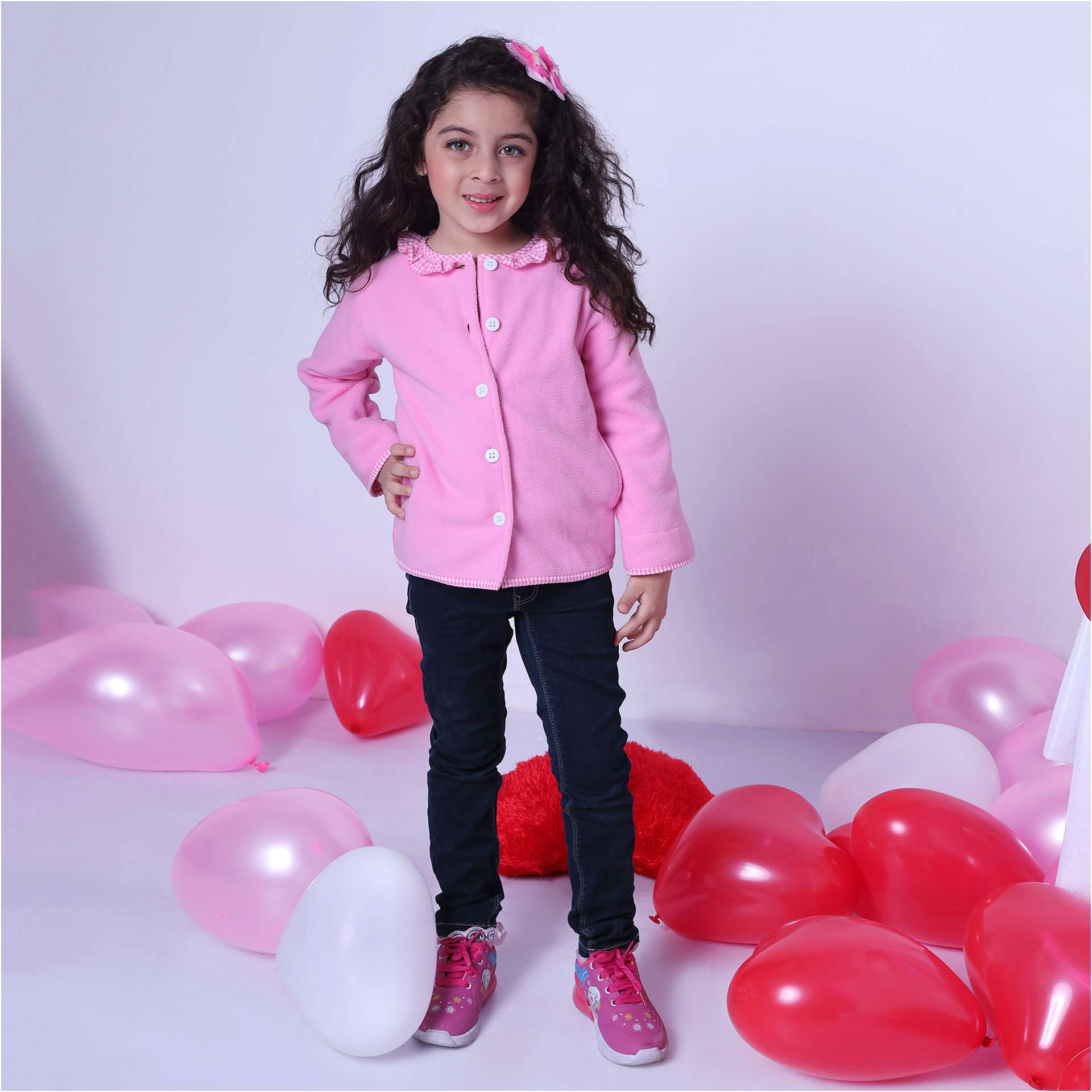 A little girl wearing fleece jacket lined in soft pink cotton, with pink gingham edging and a neckline ruffle