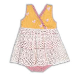 Flatlay of yellow romper with heart print, pink neckline ruffle on crossover bodice with an ivory lace skirt overlay