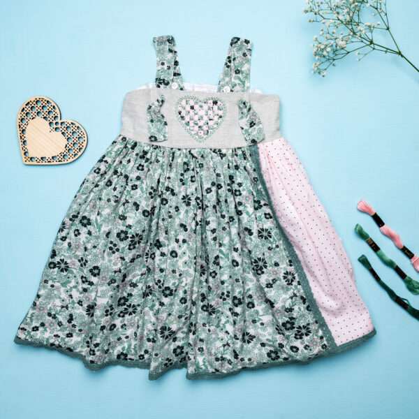 Flatlay image of strappy dress with floral print and pink dot fabric with intricate ribbon patchwork heart applique