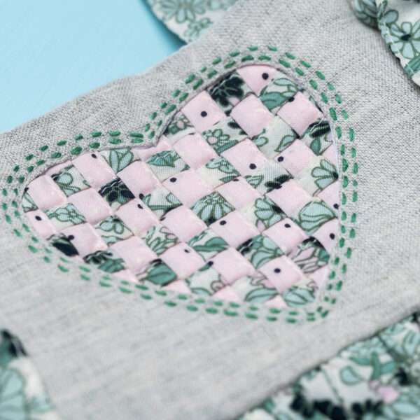 Close-up shot of a heart patchwork applique on the yoke of a sleeveless strappy shoulder dress