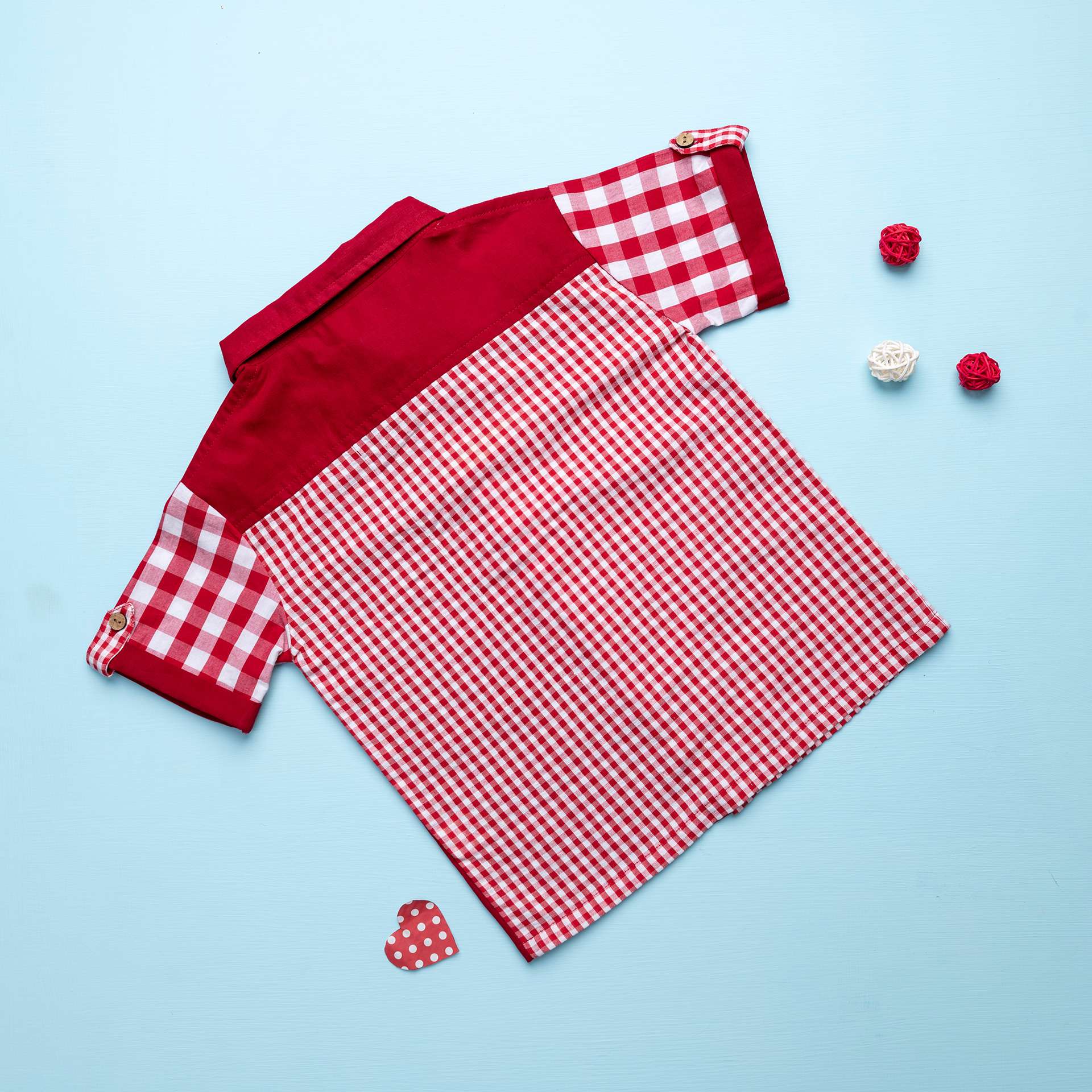 Flatlay of rear side of the red checked shirt made from a patchwork of big and micro red gingham and solid red voile