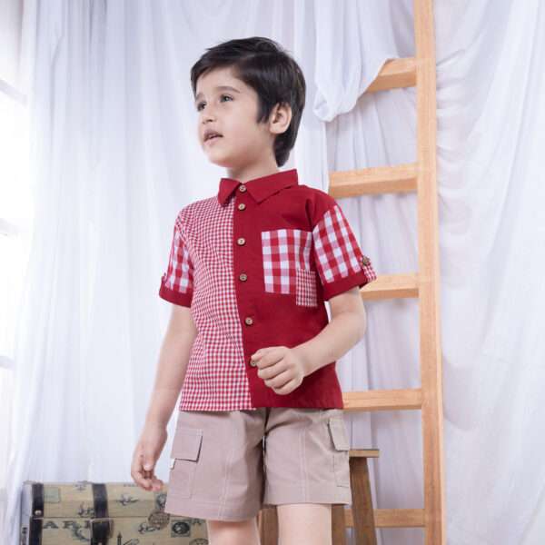 A boy posing in red checked shirt made from a patchwork of big and micro red gingham and solid red voile